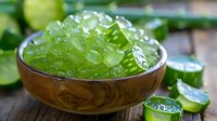 Fresh green cucumber caviar in wooden bowl with sliced cucumbers on rustic wooden background, molecular gastronomy concept perfect for restaurant menu and food design.