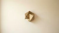 Geometric brown paper origami cube with angular folded surfaces on neutral beige background for modern minimalist design projects.