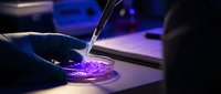 Laboratory scientist using pipette to transfer purple liquid sample in petri dish for medical research and scientific analysis in modern lab setting.