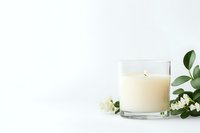 Elegant white scented candle in glass holder with fresh jasmine flowers and green leaves on white background, minimalist spa composition with copy space.