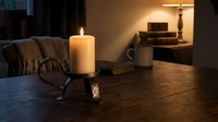 Cozy evening interior with burning candle on wooden table, warm ambient lighting creating peaceful atmosphere for relaxation and comfort at home.