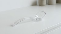 Clear transparent contact lens on white surface with soft lighting for vision correction and eye care concepts.