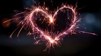 Heart-shaped sparkler light trail against dark background, creating romantic atmosphere for Valentine's Day celebrations, weddings, or anniversary events.