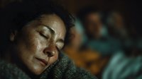 Peaceful middle-aged Caucasian woman sleeping soundly in cozy knitted sweater with warm lighting creating intimate bedroom atmosphere for rest and relaxation.