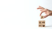 Hand placing wooden cube with food icons on white background for restaurant menu design and culinary business branding concepts.