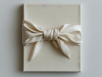 Elegant cream-colored silk bow adorns wrapped gift box against neutral background, creating minimalist luxury presentation for special occasions.