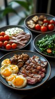 Gourmet breakfast spread with grilled steak, fried eggs, roasted mushrooms, cherry tomatoes, bacon and fresh spinach salad served on dark ceramic plates.