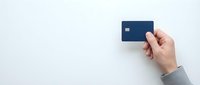 Hand holding dark blue credit card against clean white background for financial services and banking concepts.