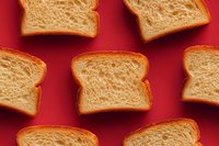 Fresh whole wheat bread slices arranged on vibrant red background for bakery advertising and healthy breakfast concepts.