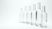 Empty clear glass bottles collection arranged in row on white background isolated for packaging design and beverage industry applications.