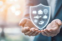 Businessman holding glowing digital shield with insurance icons for home, travel, car and life protection, symbolizing comprehensive coverage.