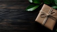 Gift box wrapped in brown kraft paper with twine bow on dark wooden background with green leaves, minimalist holiday composition for special occasions.