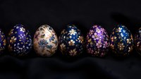 Decorative Easter eggs with floral patterns in blue, pink and gold on dark background. Traditional painted eggs showcase delicate spring flowers and ornaments.