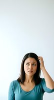 Young woman with long dark hair and Southeast Asian ethnicity wearing teal v-neck shirt, hand to head, confused or thoughtful expression against white background for portrait use.