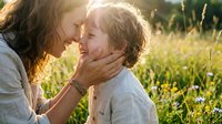 Loving mother and young son sharing tender moment in sunny meadow, warm golden hour light creating intimate family connection outdoors in natural setting.