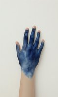 Human hand covered in blue paint or ink stains against neutral background for creative art and craft projects.