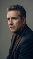 Mature Caucasian businessman with gray hair in dark suit jacket looking contemplative in professional portrait for corporate and business marketing materials.