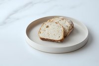 Fresh sliced white bread on minimal ceramic plate against marble background, modern food photography styling for restaurant menu and blog content.