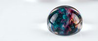 Colorful abstract resin sphere with swirling teal and purple patterns on white background, modern decorative art piece for contemporary interior design.
