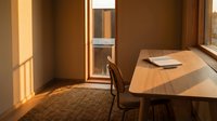 Minimalist office workspace with wooden desk, chair, and warm natural sunlight streaming through window. Suitable for business, productivity, and workspace design projects.