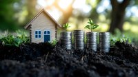 Growing investment concept with stacks of coins and small wooden house on soil, green sprouts emerging from money piles showing financial growth and property value increase.