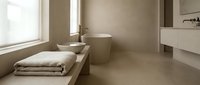 Modern minimalist bathroom with neutral beige tones, featuring a window seat with folded towels, toilet, and sink. Spa-like design for wellness and relaxation concepts.