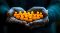 Glowing orange figures held in cupped hands against dark background symbolizing community support, team leadership, human resources and unity concept.