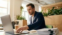 Focused businessman working on laptop in modern office with plants and natural lighting for productivity and professional success.