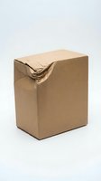Damaged brown cardboard shipping box with torn corner on white background, isolated package for e-commerce and delivery concepts.