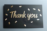 Elegant thank you card with gold lettering and scattered petals on black background, modern calligraphy style greeting design for special occasions and appreciation notes.