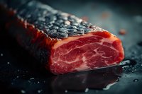 Raw marbled beef steak with black pepper crust on dark background, macro shot showing meat texture and juicy red flesh. Professional food photography.