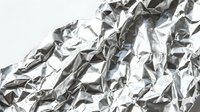 Crumpled metallic foil with reflective silver and dark gray wrinkled texture, suitable for backgrounds, packaging design, and creative overlays.