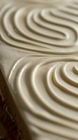 Creamy swirled texture of soft serve ice cream or frosting with smooth spiral patterns creating an elegant dessert surface. Close up macro food photography.