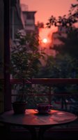 Serene balcony scene with coffee cup and potted plant silhouetted against dramatic orange sunset sky, creating peaceful evening atmosphere for relaxation and mindfulness.