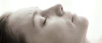 Peaceful young woman with closed eyes in serene profile view, soft lighting creating calm meditation mood for wellness and relaxation concepts.