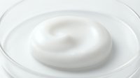 Creamy white swirl of moisturizer or skincare product in a clear container, isolated on white background for cosmetics, beauty, and wellness design projects.