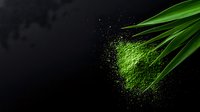 Vibrant green matcha tea powder scattered on dark background with fresh bamboo leaves, creating dramatic contrast for culinary and wellness concepts.