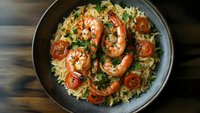 Delicious shrimp pasta with cherry tomatoes and fresh herbs served in cast iron skillet on wooden table ready for dinner.