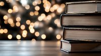 Stack of hardcover books on wooden surface against blurred warm bokeh lights background creating cozy atmospheric reading environment for literature and education concepts.