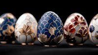 Decorative porcelain Easter eggs with elegant floral patterns in blue, white and burgundy colors on black background. Traditional ornate ceramic art pieces.