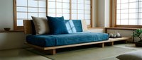 Modern minimalist sofa with blue upholstery and wooden frame in bright living room with large windows, suitable for interior design and home decor projects.
