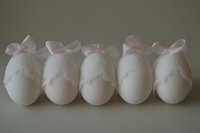 Five white Easter eggs decorated with delicate lace trim and soft pink satin bows, arranged in a row on a neutral background.