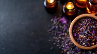 Aromatic dried flowers and herbs in wooden bowl with glowing candles on dark background, creating peaceful spa atmosphere for wellness and relaxation.