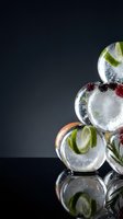 Refreshing cocktails with fresh lime slices, berries, and ice cubes stacked against dark background, perfect for beverage, bar, and hospitality design projects.