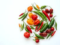 Assorted fresh chili peppers and bell peppers arranged on white background, isolated for culinary, cooking, recipe, and food design projects.