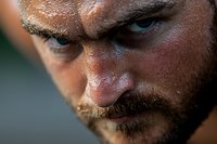 Close-up portrait of intense male face with beard showing threatening expression, dramatic lighting emphasizes eyes and facial features. For thriller or crime concepts.