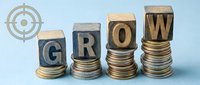 Wooden letter blocks spelling GROW on ascending coin stacks with target symbol representing business growth, financial success and investment strategy.