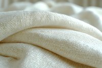 Soft cream colored linen fabric with natural texture and gentle folds creates elegant minimalist background for fashion, interior design and textile projects.