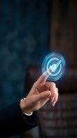 Hand touching glowing checkmark icon with blue holographic circle interface against blurred background, representing digital approval, verification, and technology solutions.
