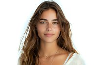 Young woman with natural makeup and flowing brown hair wearing white knit sweater and delicate necklace smiling warmly against light background.